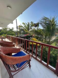 a balcony with two rocking chairs and palm trees at Mambo Boutique Nungwi in Nungwi