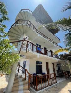 a white house with stairs and a balcony at Mambo Boutique Nungwi in Nungwi