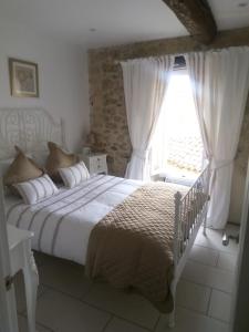 a bedroom with a white bed with a window at Maison de L'Amour Apartment Chardonnay in Assignan