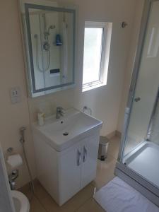 a white bathroom with a sink and a shower at London Luxury 2 Bedroom Apartment 5 min from tube station with free parking in Wanstead