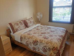 een slaapkamer met een bed met een deken en een raam bij London Luxury 2 Bedroom Apartment 5 min from tube station with free parking in Wanstead