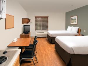 ein Hotelzimmer mit 2 Betten, einem Schreibtisch und einer Küche in der Unterkunft Extended Stay America Select Suites - Akron - South in Portage Lakes