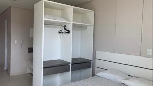 1 dormitorio con cama y armario blanco en Residencial Florida, en Bombinhas