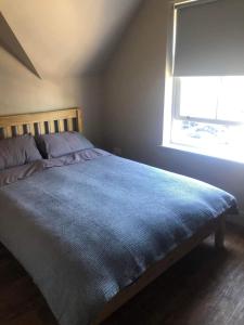1 dormitorio con 1 cama con manta azul y ventana en Mornington Harrogate en Harrogate