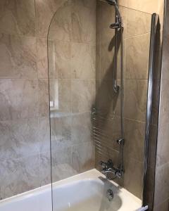 ducha con puerta de cristal junto a la bañera en Mornington Harrogate en Harrogate