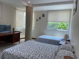 a bedroom with two beds and a desk and a television at DORAL SUITE ¡CERCA DEL AEROPUERTO! in Guayaquil