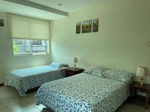 a bedroom with two beds and a window at DORAL SUITE ¡CERCA DEL AEROPUERTO! in Guayaquil