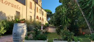 a building with a barrel in front of a garden at Locanda Menabuoi in Donoratico