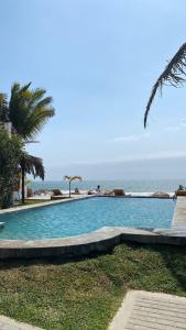 a swimming pool with the ocean in the background at Los Cocos de Vichayito in Vichayito