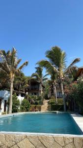 een zwembad tegenover een resort met palmbomen bij Los Cocos de Vichayito in Vichayito