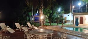patio ze stołem i krzesłami przy basenie w obiekcie Chácara Bom Jesus w mieście Caconde