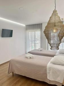 a bedroom with two beds and a television and a chandelier at Pontinha Exclusive House in Faro