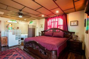 1 dormitorio con cama de madera y colcha roja en XIN Bed&Breakfast en San José