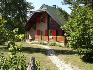 a small house with red shutters and a pathway at Zeleni Čardaci etno apartmani in Kaludjerske Bare