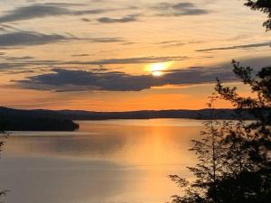 a sunset over a large body of water at Private Cliffside Chalet Nestled in Nature With Western Sunsets & Waterfront Access Near Algonquin Park- Pass Included in Barrys Bay