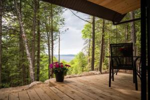 a wooden deck with a chair and flowers on it at Private Cliffside Chalet Nestled in Nature With Western Sunsets & Waterfront Access Near Algonquin Park- Pass Included in Barrys Bay