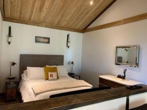 1 dormitorio con cama y espejo en la pared en Private Off Grid Cottage Nestled in Nature With Waterfront, en Barrys Bay