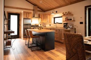uma cozinha com armários de madeira e uma ilha com bancos de bar em Private Off Grid Cottage Nestled in Nature With Waterfront em Barrys Bay