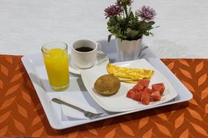 a plate of breakfast food with a glass of orange juice at Hotel Royal Plaza in Villavicencio