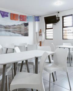 uma sala de jantar com mesas brancas e cadeiras brancas em Hotel Guivá Aeropuerto em Oaxaca de Juárez