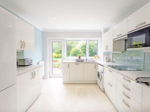 a kitchen with white cabinets and a large window at Still Waters, Emsworth in Emsworth