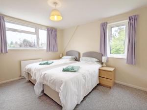 a bedroom with two beds and two windows at Still Waters, Emsworth in Emsworth