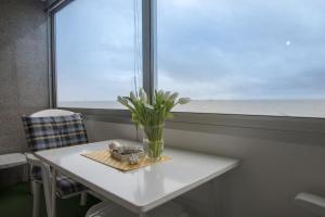 Una mesa con un jarrón de flores y una ventana. en Am-Sahlenburger-Strand-1-Whg-15, en Cuxhaven