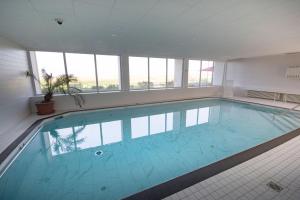 ein großer Pool in einem Gebäude mit Fenstern in der Unterkunft Am Sahlenburger Strand 1 Whg. 15 in Cuxhaven