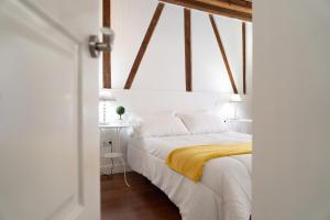 sypialnia z białym łóżkiem i żółtym kocem w obiekcie Tres Culturas Lux w mieście Toledo