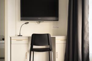 a desk with a chair and a television on a wall at Apartments Trzin-Mlake w FREE Parking in Trzin