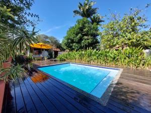 a swimming pool on a wooden deck with an umbrella at Gambá Casa Boutique in Búzios +40 photos