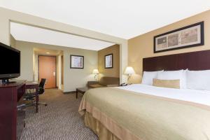 a hotel room with a large bed and a flat screen tv at Wingate by Wyndham Dayton - Fairborn in Fairborn
