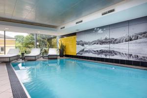 a swimming pool in a house with a mural on the wall at Wyndham Grand Salzburg Conference Centre in Salzburg