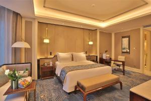 um quarto de hotel com uma cama grande e um sofá em Wyndham Qingdao em Qingdao