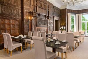 a dining room with tables and chairs and a chandelier at Wyndham Trenython Manor in Fowey