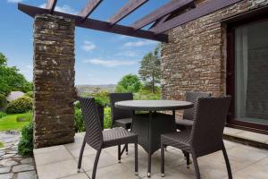 a table and chairs on a patio with a view at Wyndham Trenython Manor in Fowey