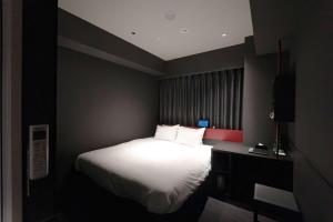 a bedroom with a bed and a desk with a white bed at Wyndham Garden Sapporo Odori in Sapporo