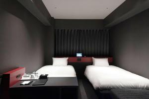 a room with two beds and a desk in it at Wyndham Garden Sapporo Odori in Sapporo