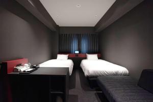 a hotel room with two beds and a couch at Wyndham Garden Sapporo Odori in Sapporo