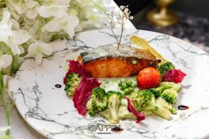 a plate of food with a piece of meat and broccoli at Cappo Aparthotel in Veliko Tŭrnovo