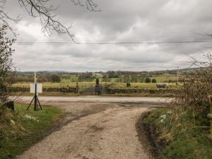 a dirt road leading to a field with cows at Hideaway in Leek
