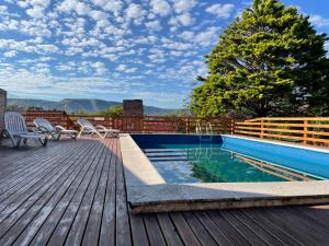 una piscina con 2 sillas y una terraza de madera en Casa El Descanso en San Antonio de Arredondo
