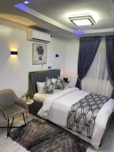 um quarto com uma cama e uma cadeira em Morak Homes - Luxury 4 bed home with PS5, 24hrs electricity, Super fast Wifi, Snooker, Games room - in a secured estate em Abuja