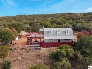 an aerial view of a house in the woods at Entire 2br 2ba hilltop view home Sleeps 7 pets 4 acres Jacuzzi Central AC Kingbeds Free Wifi-Parking Kitchen WasherDryer Starry Terrace Two Sunset Dining Patios Grill Stovetop Oven Fridge OnsiteWoodedHiking Wildlife CoveredPatio4pets & Birds Singing! in Marble Falls