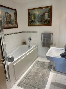 a white bathroom with a tub and a sink at Executive Corporate Penthouse in Woking