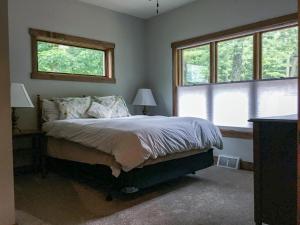 a bedroom with a bed and two windows at Lakefront Home 4 Bedroom 4 Bath Sleeps 12 in Waupaca
