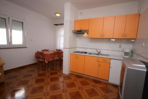 a kitchen with orange cabinets and a table in it at Apartment Pag 6311c in Pag