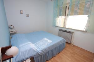 a bedroom with a bed with a blue blanket and a window at Apartments with a parking space Valbandon, Fazana - 7215 in Štinjan