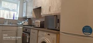 a kitchen with wooden cabinets and a washer and dryer at Remarkable 2-Bedroom Apartment with an EnSite in London