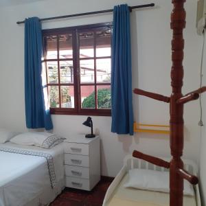 a bedroom with a bed and a window with blue curtains at Casa agradável in Cabo Frio